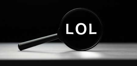 Magnifying glass with text LOL on wooden table. Concept of searchの写真素材