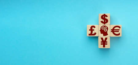 wooden blocks in the form of a cross with currency symbols of the world on blue background.の写真素材