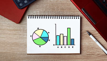 Business growth graph on a sheet of Notepad. Notepad on desk with laptop and a pen.の写真素材