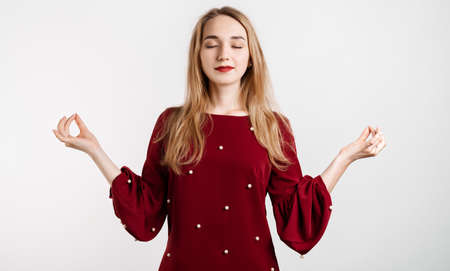 Attractive calm European girl with long blonde hair delighted meditating hands sideways nirvana lotus pose, breathing practice yoga, isolated over white background.の写真素材