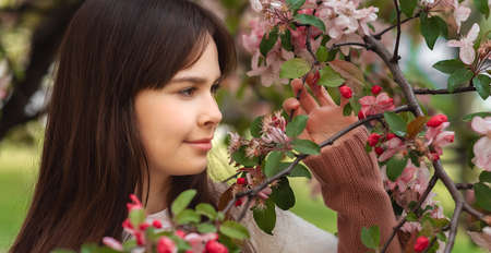 Closeup beautiful young brunette girl 11-12 years under the flowering pink tree, lifestyleの写真素材