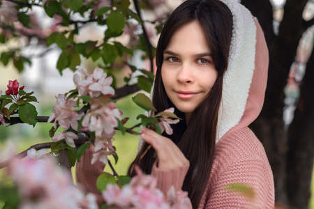 Closeup beautiful young brunette girl 11-12 years under the flowering pink tree, lifestyleの写真素材