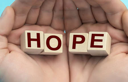 HOPE Word Written In Wooden Cube. HOPE text concept. Men's hands, cube wooden block. Top viewの写真素材