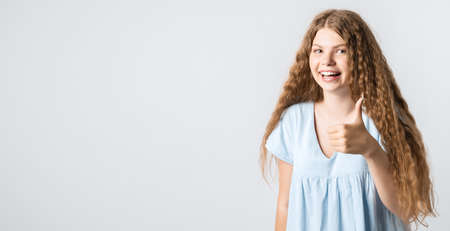 Good job. Pretty carefree modern stylish European girl with curly long hair making gesture OK, as if saying that everything is finee, white background. Copy space for your textの写真素材