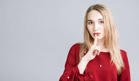 Emotional European young woman with long blonde hair dressed in casual clothes, keeping index finger...