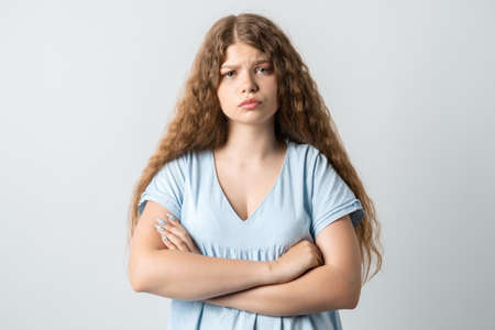 Offended pensive girl with curly long hair posing isolated on white background. People lifestyle...