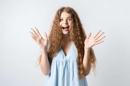 Positive human emotions, reaction and astonishment. Surprised girl with curly long hair opening eyes widely and gesturing emotionally, excited because receives surprise from boyfriend, feels gladの写真素材