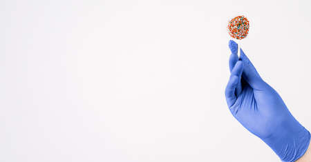 Closeup of human hand in blue surgical gloves holding and showing colorful candy in hand. Isolated...
