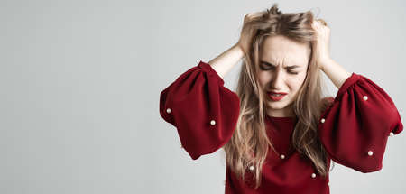 Oh NO. Photo of beautiful girl with long blonde hairs, with closes eyes, astonished holding hands on head. Problems, surprise, fear, fobia conceptの写真素材