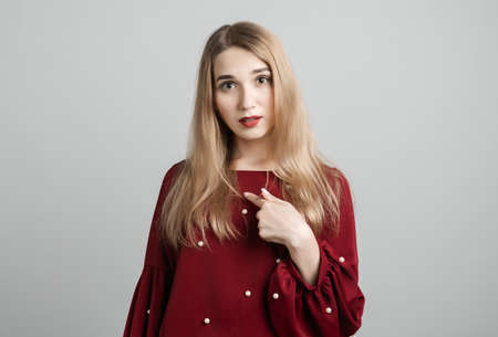 Me. Portrait of indignant girl with long blonde hair startled by offensive words, points at herself with for finger, opens mouth in surprises, has dissatisfied expression, wears casual clothesの写真素材