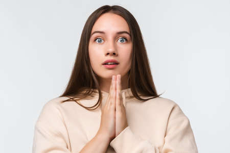 Image of pleased brunette woman with long hair smiling and holding palms together dressed in casual clothes. She meditating, praying for peace and love, having calm and peaceful facial expressionの写真素材