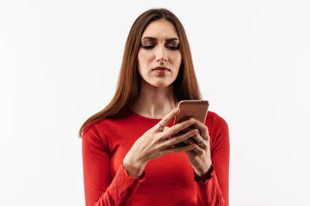 Young woman with long chestnut hair using mobile phone. New useful application, uses fast unlimited...
