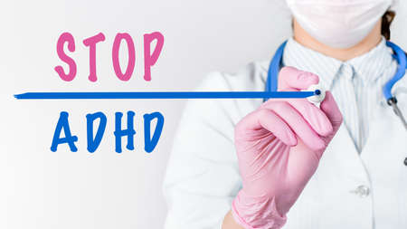 Close up female doctor in a white coat with stethoscope and pink sterile gloves writing text STOP...