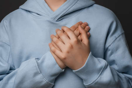 Thank you. Cropped close up of boy10-12 years old, dressed in casual clothes presses palms to heart, being grateful for gift, says you are always in my heart. Positive emotionsの写真素材