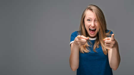 Successful Young female with blonde straight hair, dressed in blue t shirt, smiling happily,...
