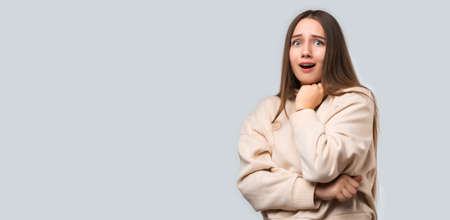 Studio shot of Scared young woman with long chestnut hair, dressed in casual clothes, isolated on white background. Human emotions, facial expression concept. Copy space for your textの写真素材