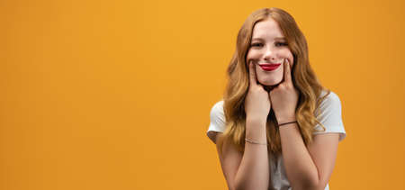 Young beautiful woman in casual t-shirt standing and pretends to smile with stretches her mouth into...
