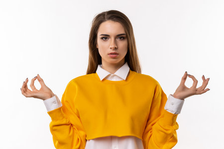 Keep calm and carry on. Portrait of relaxed young woman holding spread hands with zen gesture while meditating, feel patience and peace, practice yoga, white backgroundの写真素材