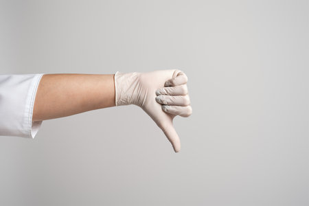 Cropped view of doctor showing thumb down, isolated over gray background. Medicine, profession and healthcare concept. Protect yourselfの写真素材