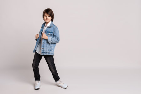Handsome fashion little boy 11-13 years old in jean jacket posing and dancing in studio. Model Test. Fashion and people concept. Place for adの写真素材