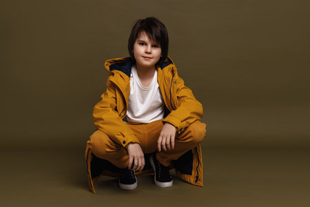 Portrait of young boy 11-13 years old posing in studio on green background. Casual style. Stylish shooting in studioの写真素材