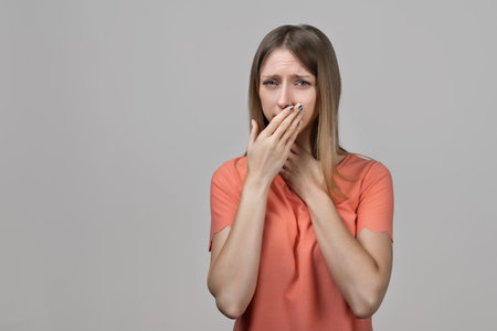 Throat pain. Young blond woman holding her inflamed throat. Portrait of woman suffering from cold, flu, sickness with sore throat inflammation, woman health care. Medical conceptの写真素材