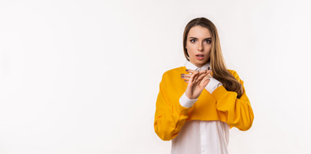 Portrait of startled young brunette woman raising hands and gasping worried, staring shocked and confused at camera. Studio shot, white background. Mock up copy spaceの写真素材