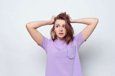 Portrait of girl in casual t shirt in panic grabbing her head in fear or frustration. Stress and...