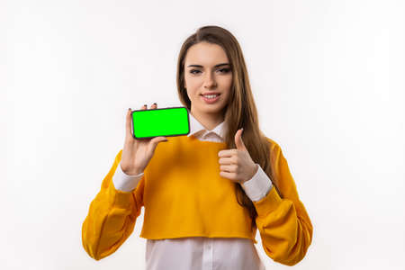Note that. Pretty young brunette woman in casual clothes is showing smartphone blank screen in her...