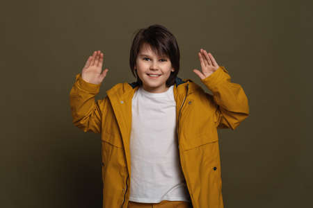 Emotional little boy express overjoy and surprised, spread hands sideways and smiling, showing astonishment and shock, isolated on green backgroundの写真素材