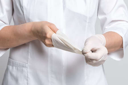 Cropped view of doctor takes off a white latex gloves. Medicine and healthcare concept
