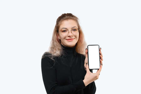 Note that. Smiling young woman showing empty smartphone screen to show advertisement, standing...
