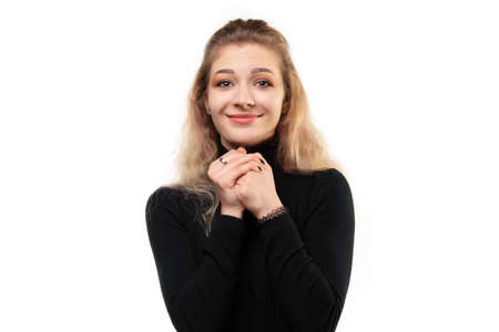 Close up portrait of dreamy blonde girl making wish, daydreaming about having something, clench fists close to chest, asking help. Luck, celebration and dreams conceptの写真素材