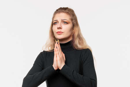 Close up calm blonde girl prays in harmony, keeps palms pressed together in praying gesture. Human...