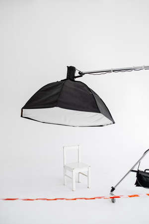 Preparation for studio shooting: empty white chair and studio lighting. Empty studio closedの写真素材