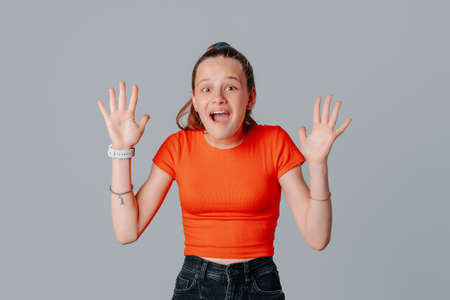 Excited brunette teen girl hear big news, receive surprise, gasping amazed, raising hands up...