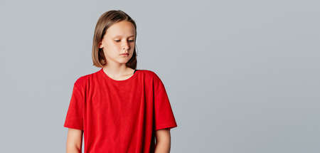 upset brunette teen girl looks away like she is very disappointed, very sad or doesn't want to hear anything, standing over gray background. Young emotional womanの写真素材