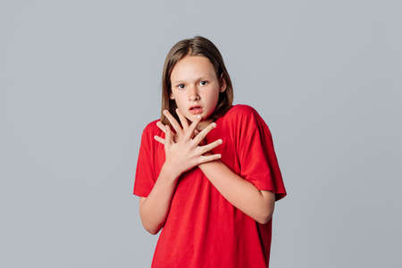 Shocked and worried brunette teen girl gasp, looking startled at camera, witness disaster, standing over gray background. Young emotional womanの写真素材