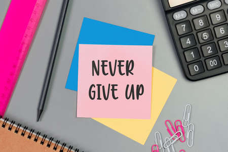 The words Never give up written on a sticky note paper. Closeup of a personal agenda. Top view. Conceptual photoの写真素材