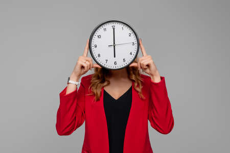 Young woman Holding Big Clock Covering her Face, she wonders how much time passed, standing in red...