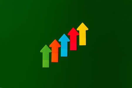 Paper sticky notes in shape of arrow pointing up on green background. Top view