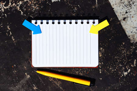 Blank notepad with pen and sticky notes in shape of arrow on vintage background, top view. Copy...