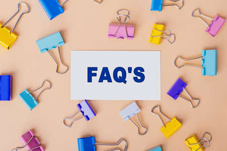 FAQ frequently asked questions - text on white card. Top view image of business card and with many paper clips on beige background. flat lay designの写真素材