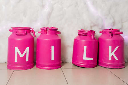 Still life with metal vintage milk can. Vintage pink storage containers milk on white background....