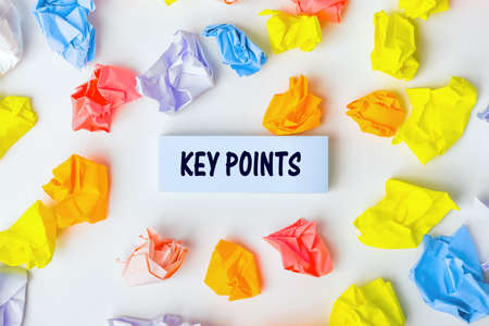 Blue sticky note with the text KEY POINTS and some colorful crumpled paper balls around it on white background, text concept. Still life, Flatlay design, View from aboveの写真素材