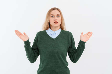 Shocked excited surprised young blonde woman 20s, wearing casual clothes, spreading hands, looking impressed with disbelief . Indoor studio shot on white backgroundの写真素材