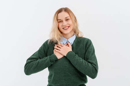 Touched tender smiling blonde woman gladly receive praises, hold hands on heart and grinning...