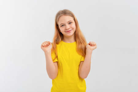 Smiling positive, attractive teen girl wearing casual yellow tshirt, feeling happy looking to camera standing isolated on white backgroundの写真素材