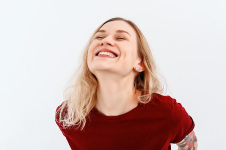 Young emotional woman. Close up portrait of young blonde woman 20s, wearing casual red t shirt. Indoor studio shot on white background. Human emotions, facial expression conceptの写真素材