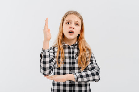 Beautiful teen girl with blonde hair wearing casual yellow t shirt, stands with his hand raised up over white studio background, smiling and gesturing hand. education and school conceptの写真素材